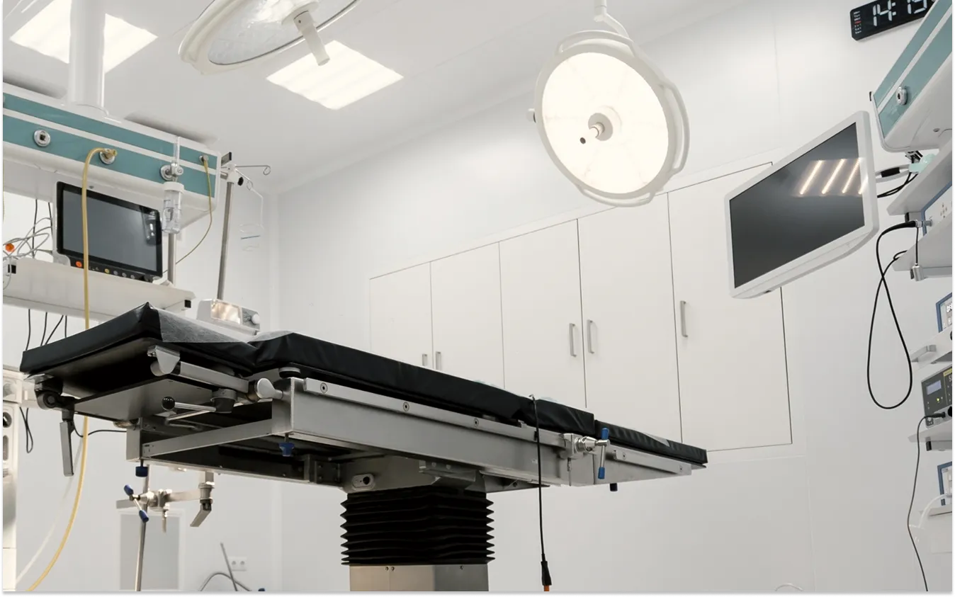 Clean, modern operating room with an operating table, ceiling lights and monitoring equipment.